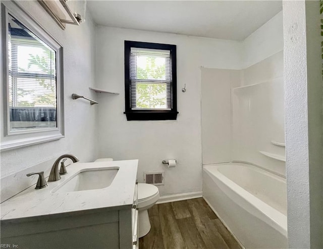 bathroom with wood finished floors, vanity, baseboards, toilet, and visible vents