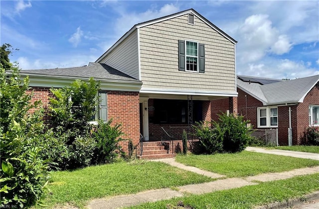 view of front of property featuring brick siding, covered porch, and a front yard