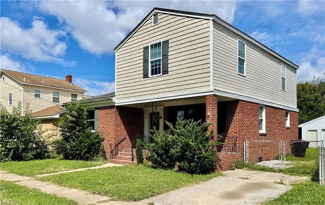 traditional-style house with brick siding, covered porch, a front lawn, and fence
