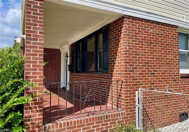 view of side of home with covered porch and brick siding