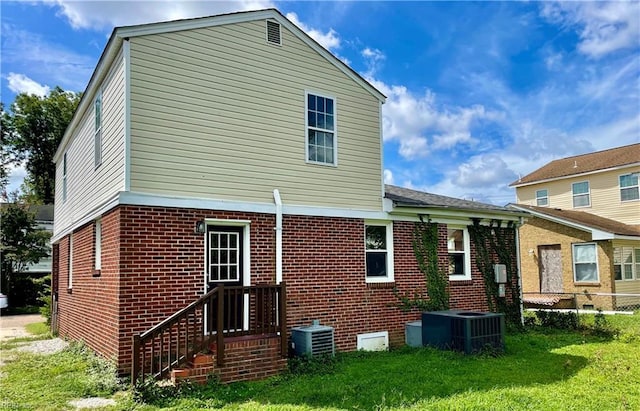 back of house featuring brick siding, fence, a yard, and cooling unit