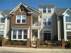townhome / multi-family property featuring a balcony and a fenced front yard