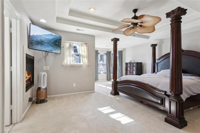 carpeted bedroom with a glass covered fireplace, baseboards, visible vents, and recessed lighting