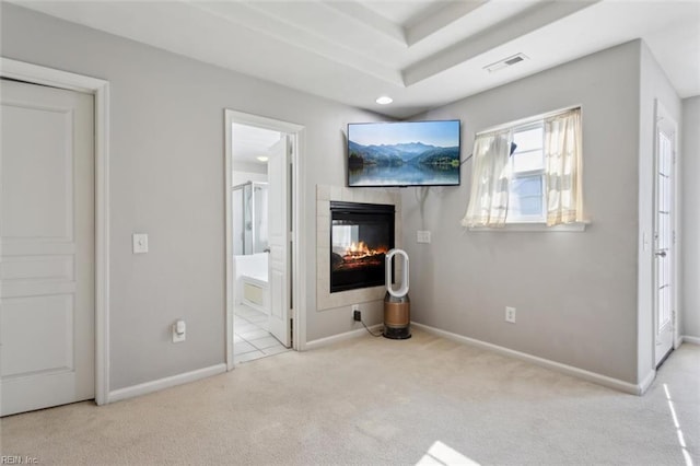 unfurnished bedroom with baseboards, visible vents, carpet, a multi sided fireplace, and ensuite bath
