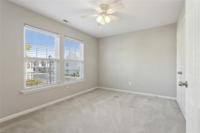 unfurnished room featuring visible vents, light carpet, a ceiling fan, and baseboards