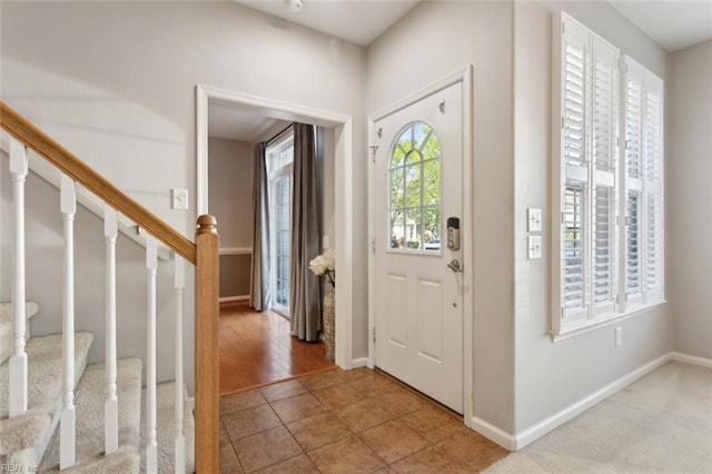 entryway featuring baseboards, stairs, and light tile patterned floors