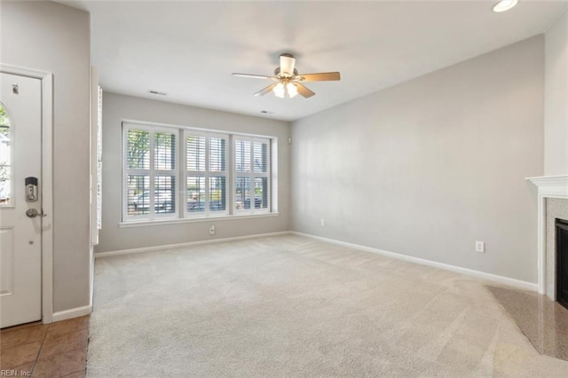 unfurnished living room featuring a glass covered fireplace, baseboards, carpet, and ceiling fan