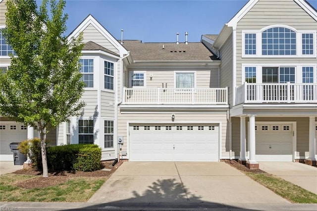 view of front of property featuring an attached garage, driveway, a balcony, and roof with shingles