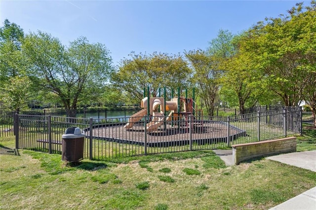 community playground featuring fence, a lawn, and a water view