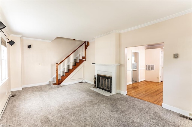 unfurnished living room with a fireplace with flush hearth, carpet floors, ornamental molding, and visible vents