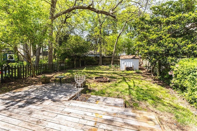 view of yard with a fenced backyard, an outdoor structure, an outdoor fire pit, a storage unit, and a deck