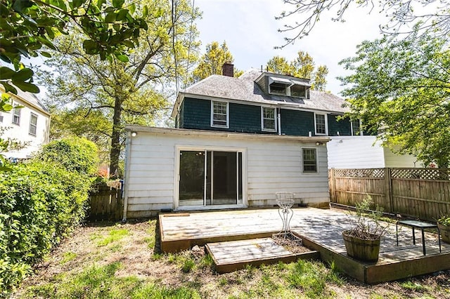 rear view of house featuring fence, a chimney, and a deck