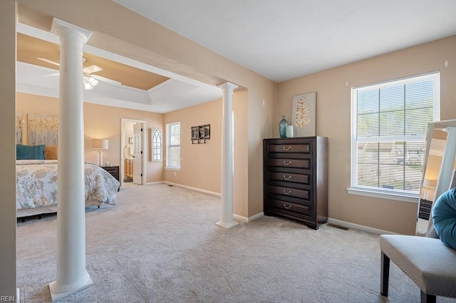 carpeted bedroom featuring baseboards, a tray ceiling, and ornate columns