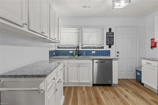 kitchen featuring a sink, dishwasher, light wood-style flooring, white cabinetry, and visible vents