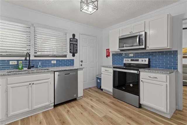 kitchen with decorative backsplash, appliances with stainless steel finishes, a sink, and white cabinetry