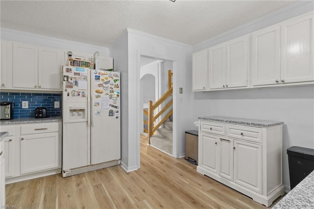 kitchen featuring white fridge with ice dispenser, light wood finished floors, and white cabinets