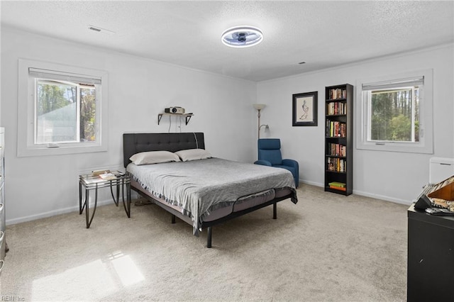 bedroom with light colored carpet, multiple windows, a textured ceiling, and visible vents