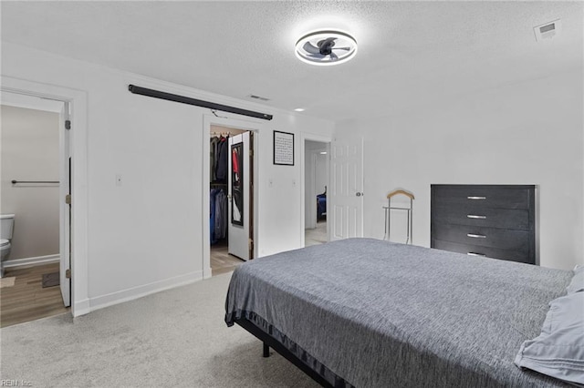 bedroom with a spacious closet, visible vents, a closet, baseboards, and a textured ceiling