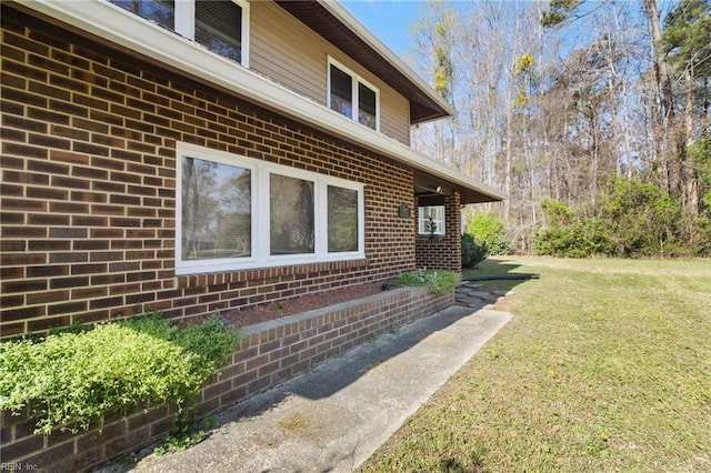 view of property exterior with brick siding and a yard