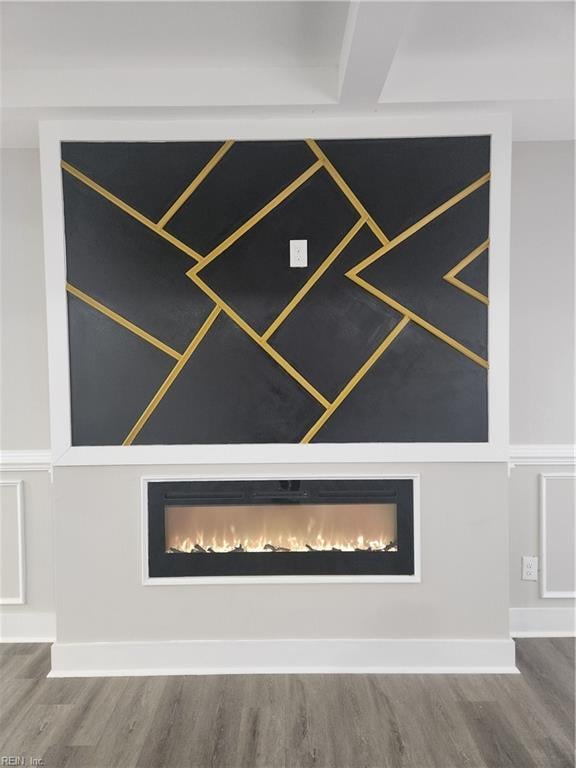 room details with wood finished floors, baseboards, and a lit fireplace