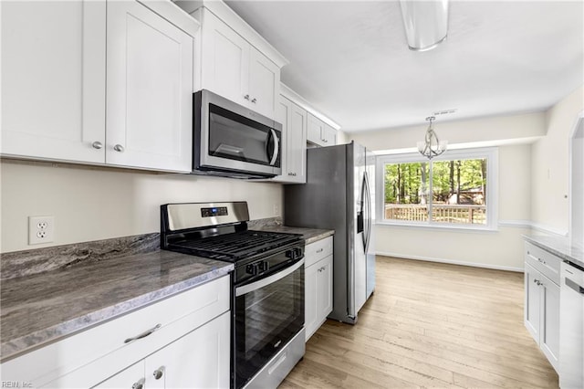 kitchen featuring white cabinets, light stone countertops, light wood-style flooring, appliances with stainless steel finishes, and a notable chandelier