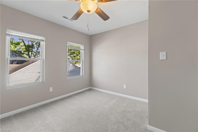 carpeted empty room featuring visible vents, a ceiling fan, and baseboards