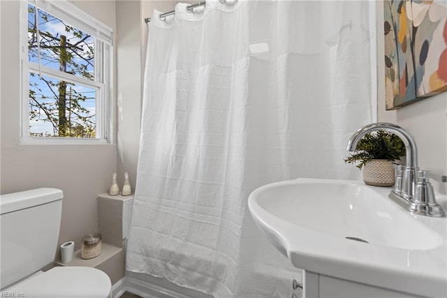 bathroom with a sink, shower / bathtub combination with curtain, and toilet