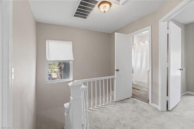 hall featuring baseboards, carpet flooring, and visible vents