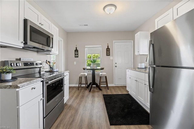 kitchen featuring white cabinetry, wood finished floors, stainless steel appliances, and visible vents