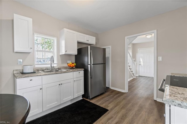 kitchen featuring wood finished floors, freestanding refrigerator, a sink, and white cabinetry