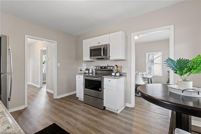 kitchen with white cabinets, wood finished floors, and appliances with stainless steel finishes