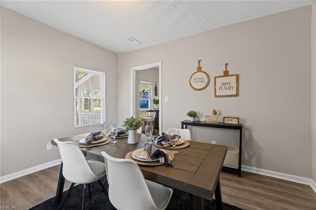 dining room featuring wood finished floors, visible vents, and baseboards