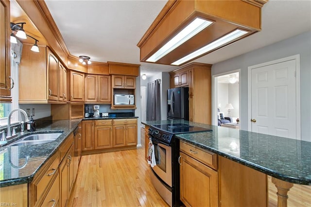 kitchen with black refrigerator with ice dispenser, light wood-type flooring, stainless steel electric range oven, and a sink