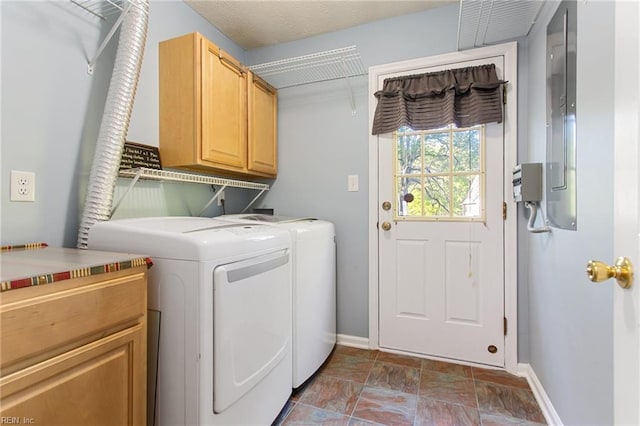 washroom with cabinet space, stone finish floor, baseboards, and washer and clothes dryer