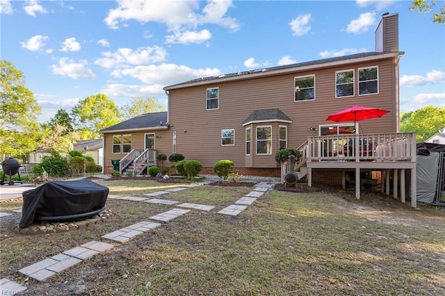 rear view of property featuring a lawn, a chimney, stairs, and a deck