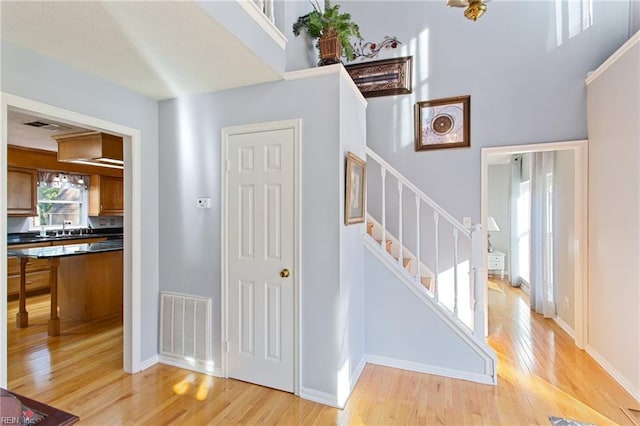 stairway with a towering ceiling, wood finished floors, visible vents, and baseboards