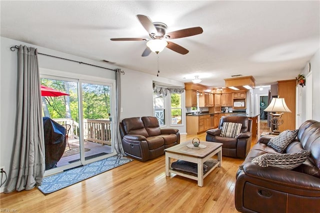 living area featuring light wood-type flooring, a ceiling fan, and visible vents