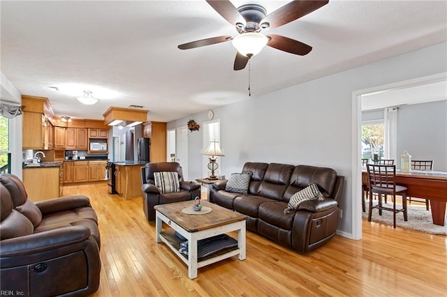 living area featuring light wood finished floors, a wealth of natural light, and ceiling fan