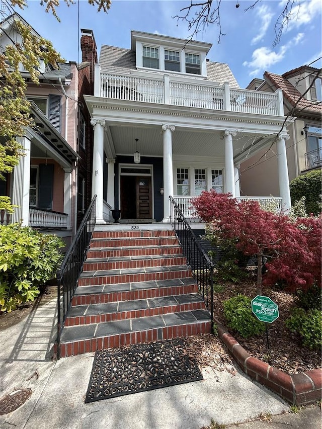 view of exterior entry with a porch and a balcony