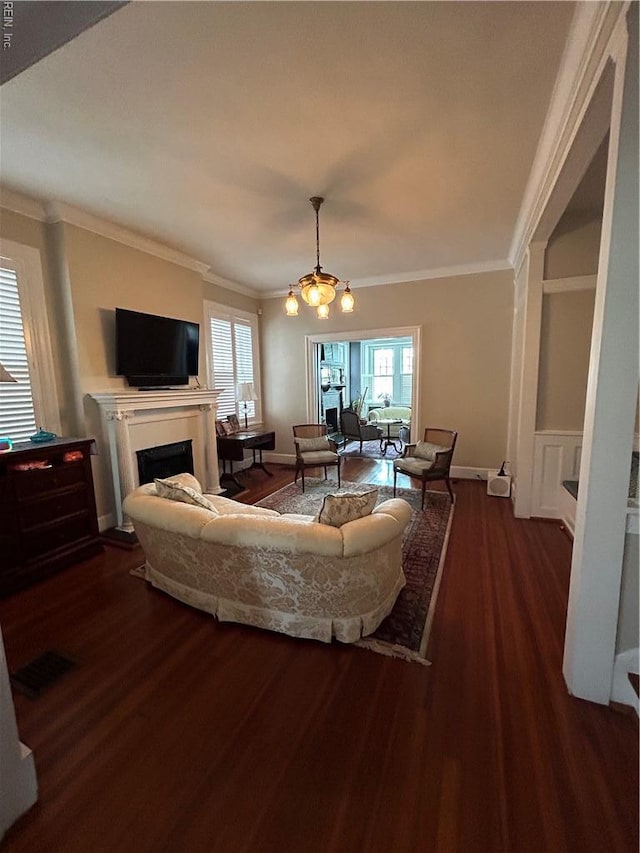 living room featuring crown molding, a fireplace, a chandelier, visible vents, and dark wood-style floors