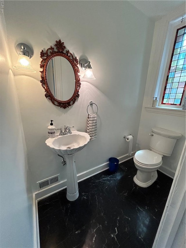 bathroom with baseboards, marble finish floor, toilet, and visible vents