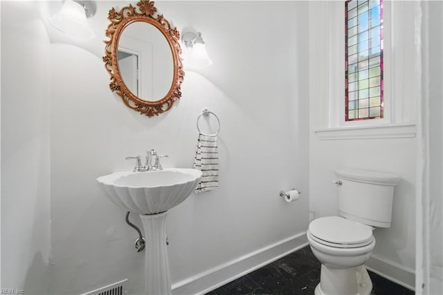 half bath featuring toilet and baseboards
