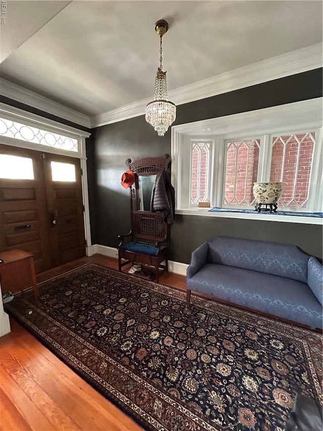 foyer entrance with crown molding, baseboards, a notable chandelier, and wood finished floors