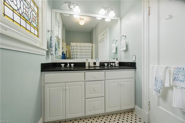 full bath with double vanity, baseboards, a sink, and a shower with shower curtain