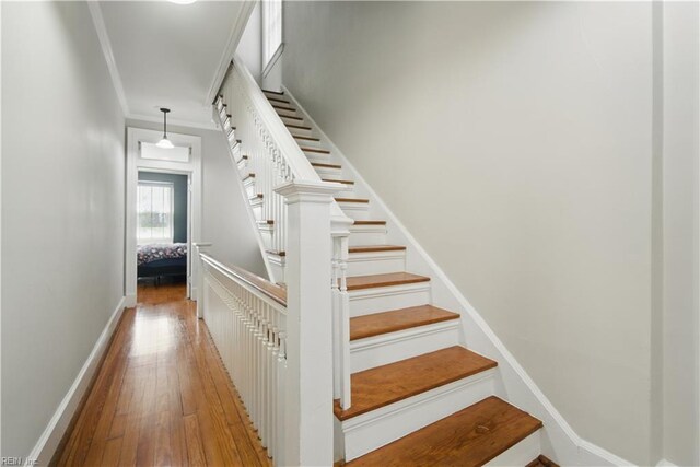 stairway featuring crown molding, baseboards, and hardwood / wood-style flooring