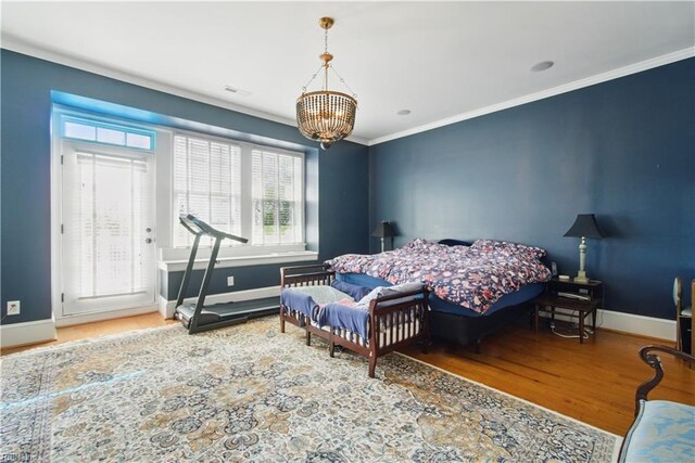 bedroom with baseboards, ornamental molding, wood finished floors, and a notable chandelier