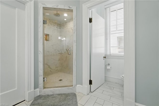 bathroom featuring toilet, baseboards, a marble finish shower, and marble finish floor