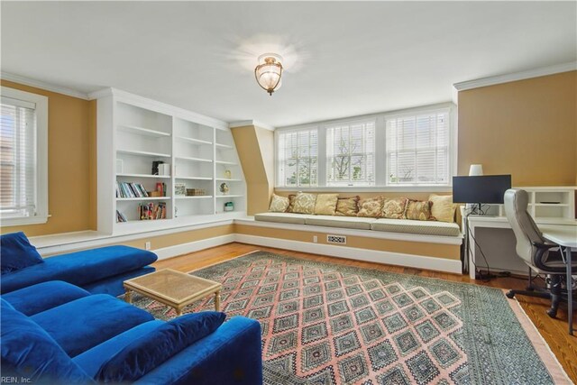 living area with ornamental molding and wood finished floors