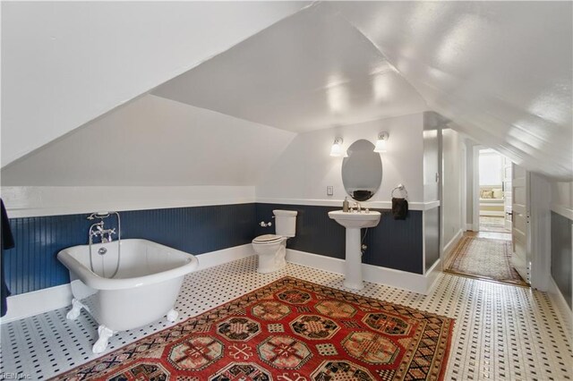 full bathroom with toilet, baseboards, vaulted ceiling, and a soaking tub