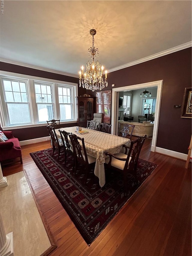 dining area featuring baseboards, ornamental molding, wood finished floors, and a notable chandelier